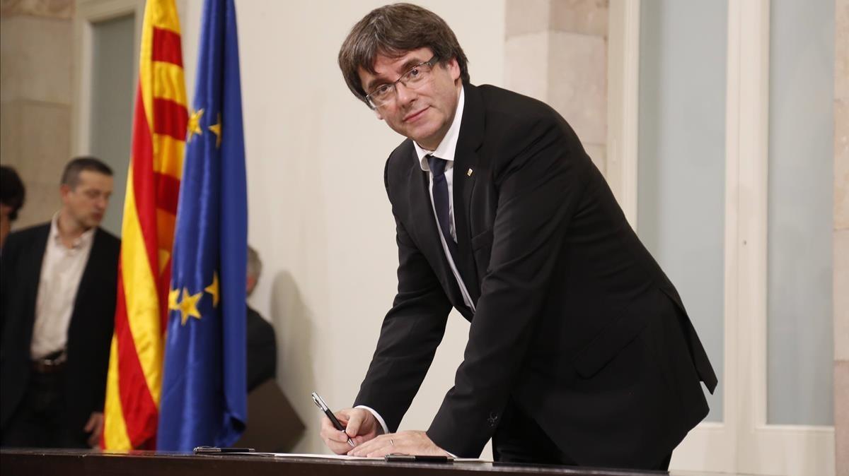 El president Carles Puigdemont en el momento de firmar la declaración, tras el pleno.