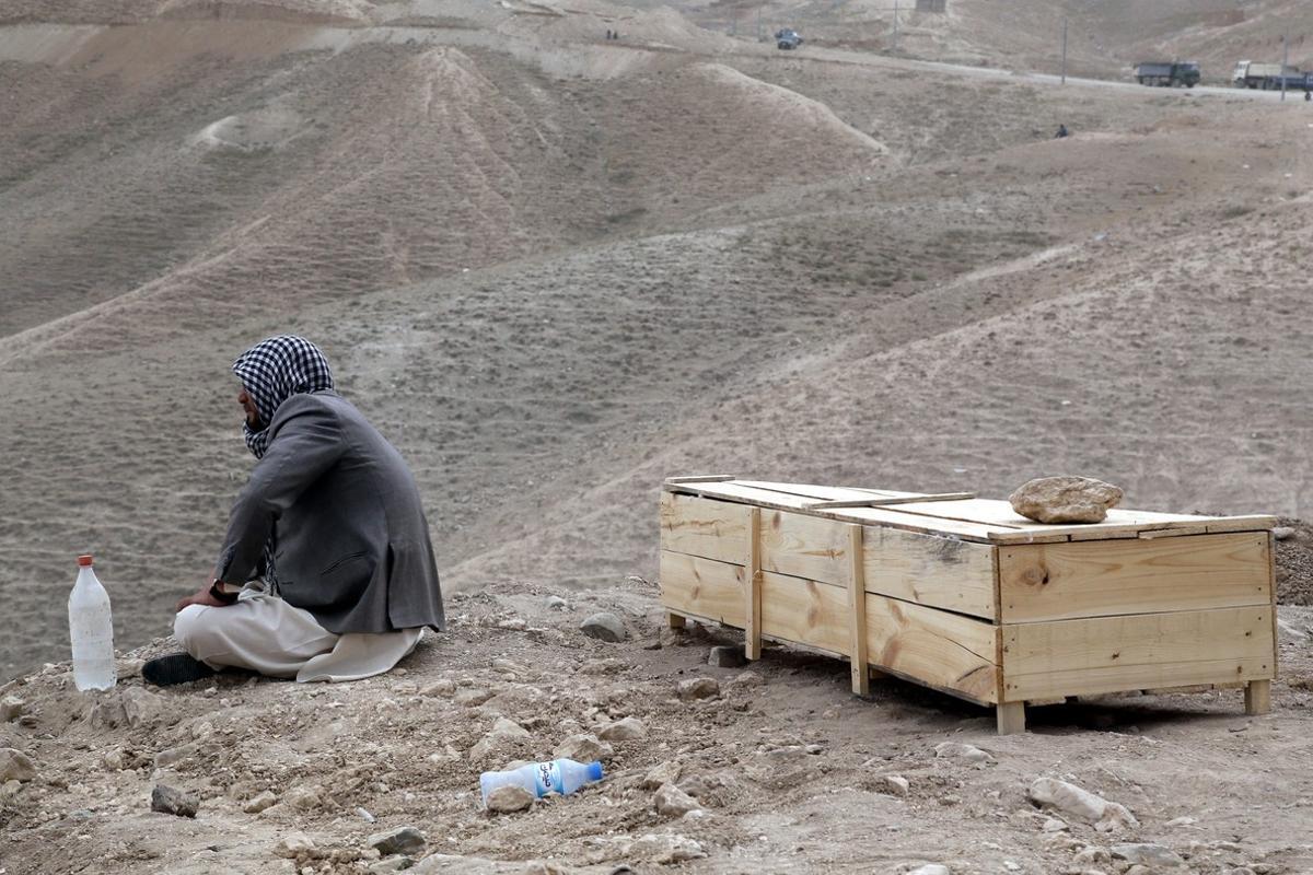 KAB01. Kabul (Afghanistan), 24/07/2016.- A man sits beside the coffin of his relative who was killed in a suicide bomb attack in Kabul, Afghanistan, 24 July 2016. According to reports at least 80 people were killed and more than 550 injured when a bomb exploded a day before in Kabul, as thousands of people from Hazara minority were protesting the proposed route of the Turkmenistan, Uzbekistan, Tajikistan, Afghanistan and Pakistan (TUTAP) power line, calling on the government to re-route the line through Bamiyan province which has a majority of Hazara population. (Afganistán, Atentado, Tadjikistan) EFE/EPA/JAWAD JALALI