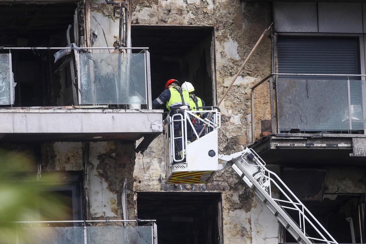 Dos bomberos inspeccionan el edificio, tras el incendio en el edificio de Campanar.