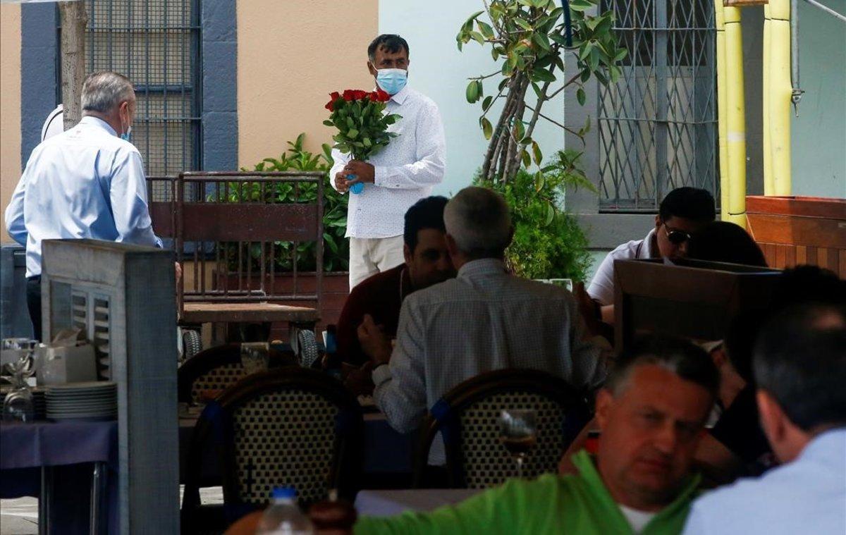 Un vendedor ambulante espera para ofrecer sus rosas en una terraza de la Barceloneta.