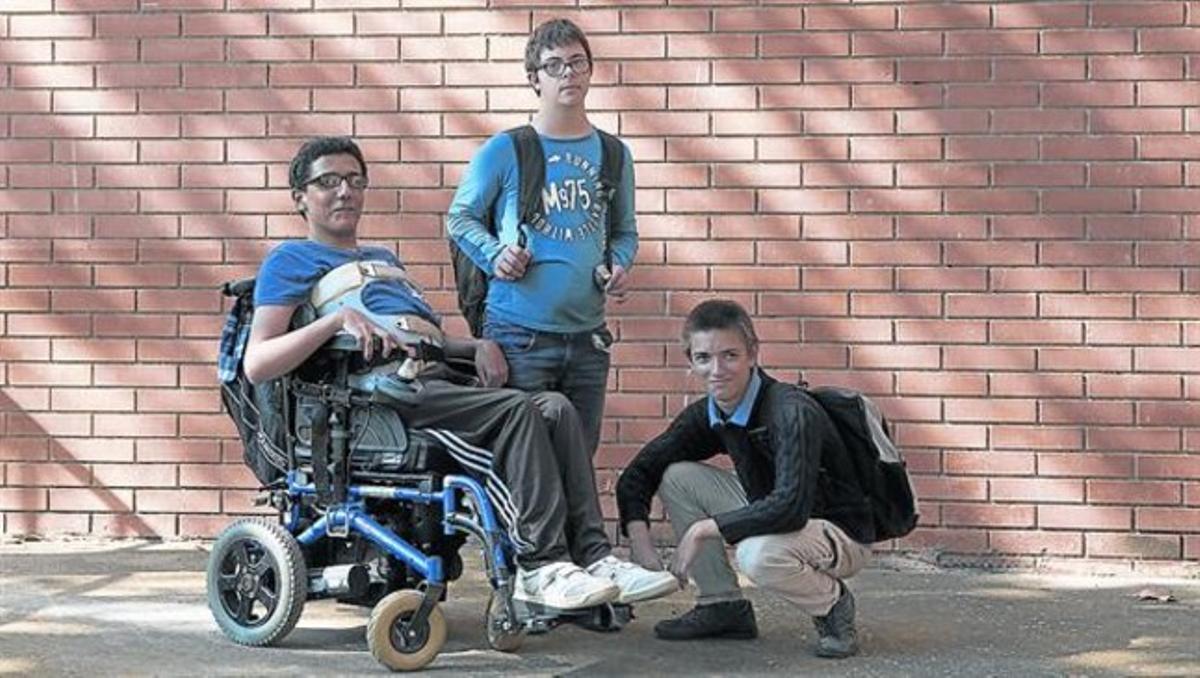Martí (en el centro) y Òscar (agachado), con su compañero de curso Youssef, a la salida del instituto Icària de Barcelona, ayer.