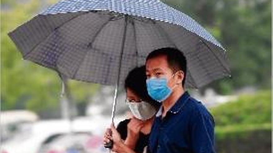 Una parella es protegeix de la pluja a la zona del port de Tianjin.