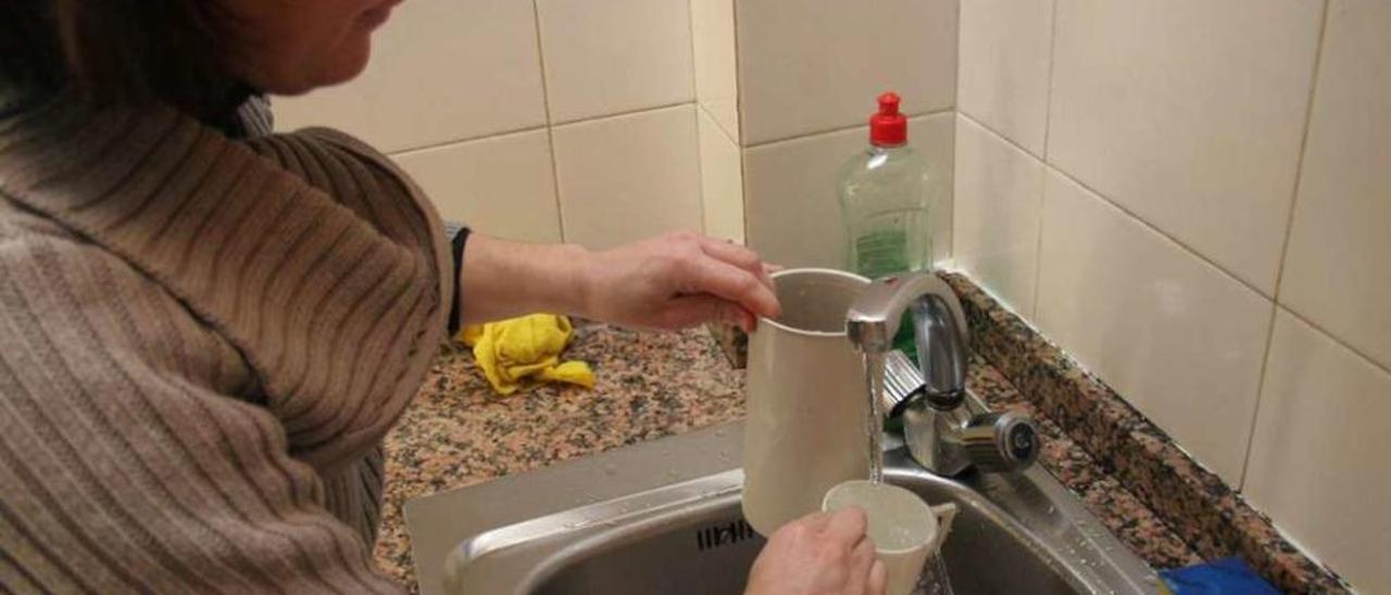 Una usuaria hace uso del abastecimiento público de agua en su domicilio. // Iñaki Osorio