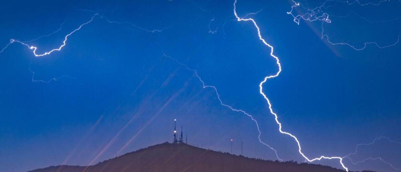 Imagen de madrugada con los rayos iluminando el centro emisor de telecomunicaciones del Monte Faro, entre las parroquias de Meira y Domaio