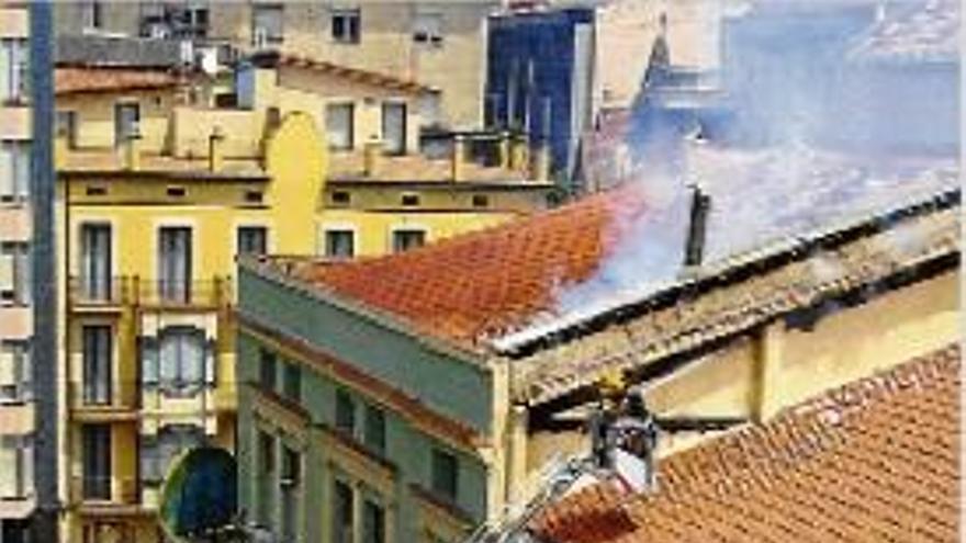 Bombers treballant en l&#039;extinció del foc des de la teulada de l&#039;edifici