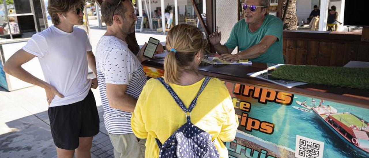 Los turistas piden información en los puestos de las empresas para conocer los trayectos que pueden realizar desde Sant Antoni en barco.