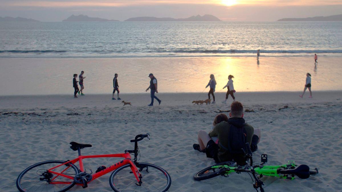 Varias personas pasean por la playa de Samil, en Vigo.