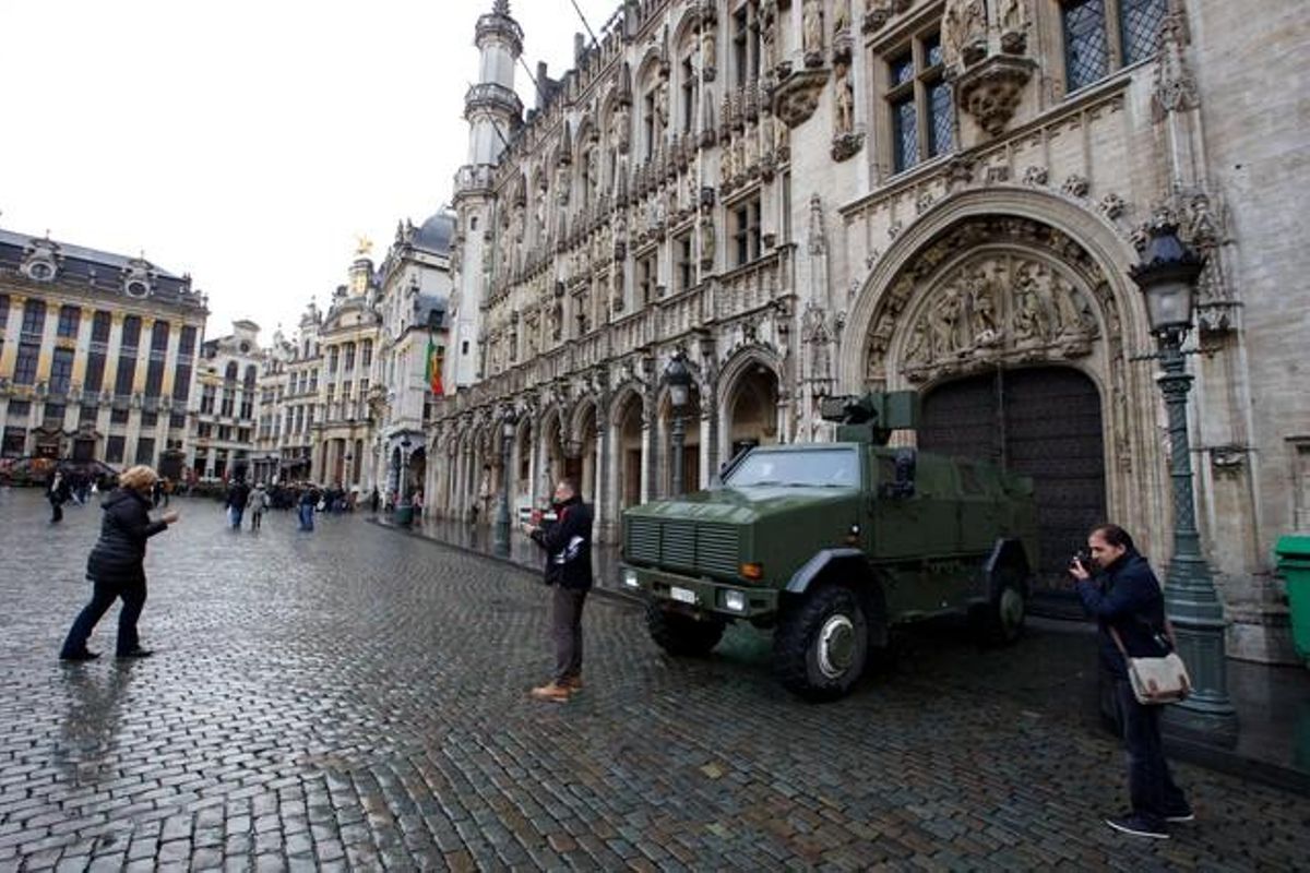 Dues persones es fotografien davant d’un vehicle militar a la Gran Plaça, que es manté solitària.