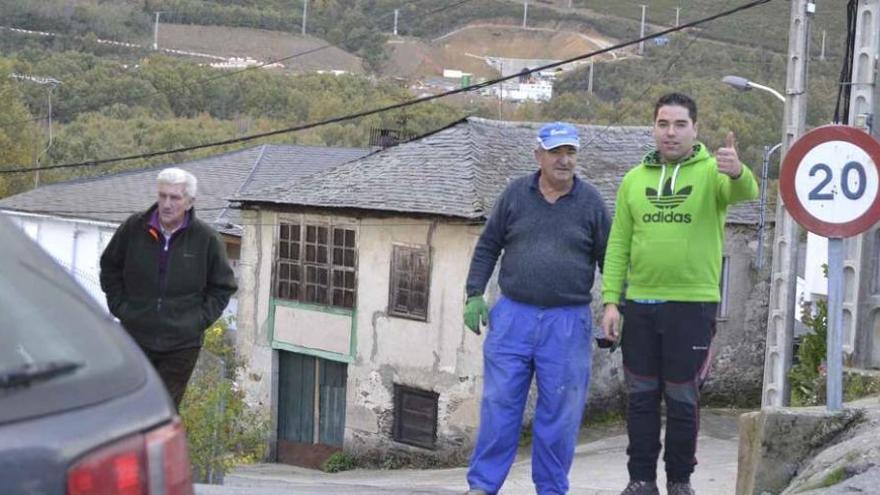 Tres personas en Requejo, con la bocana de uno de los túneles en la ladera del fondo.