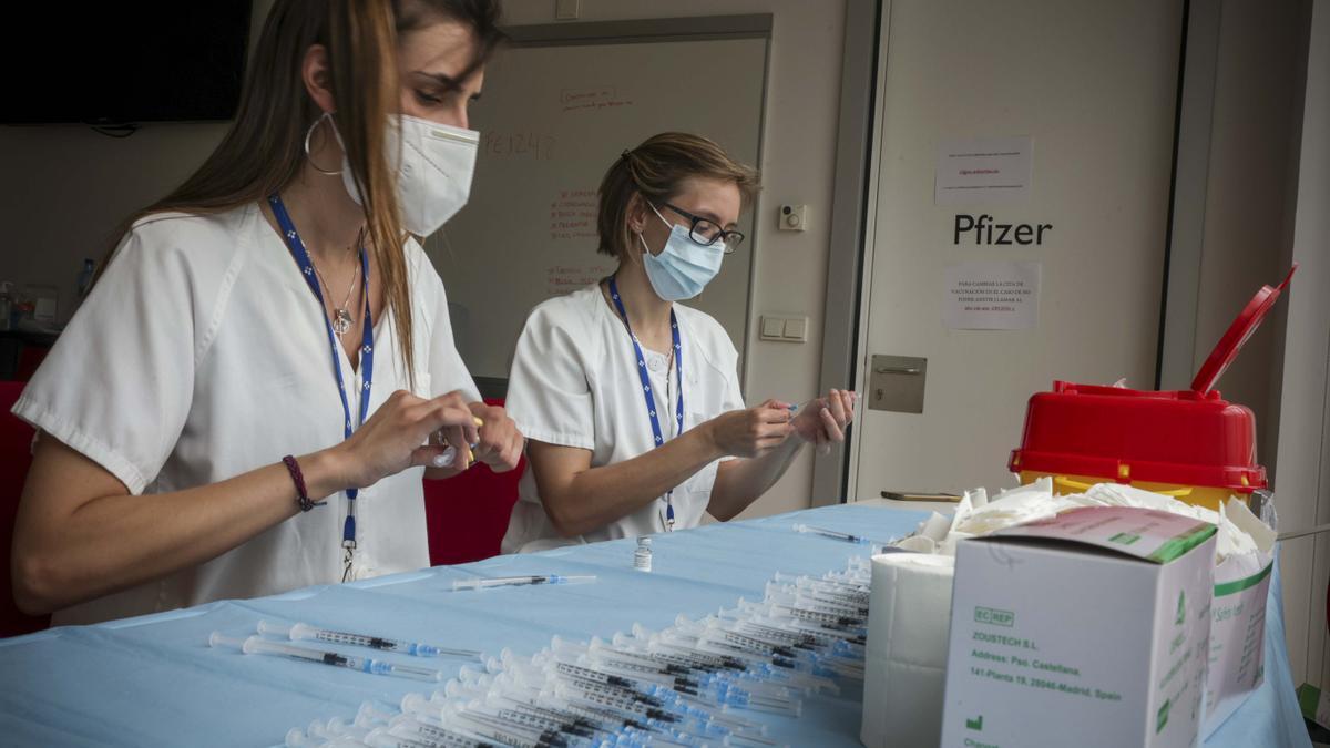 Alicia Fernández y Aurora Muñíz preparan las jeringuillas en en cubo 10 del HUCA