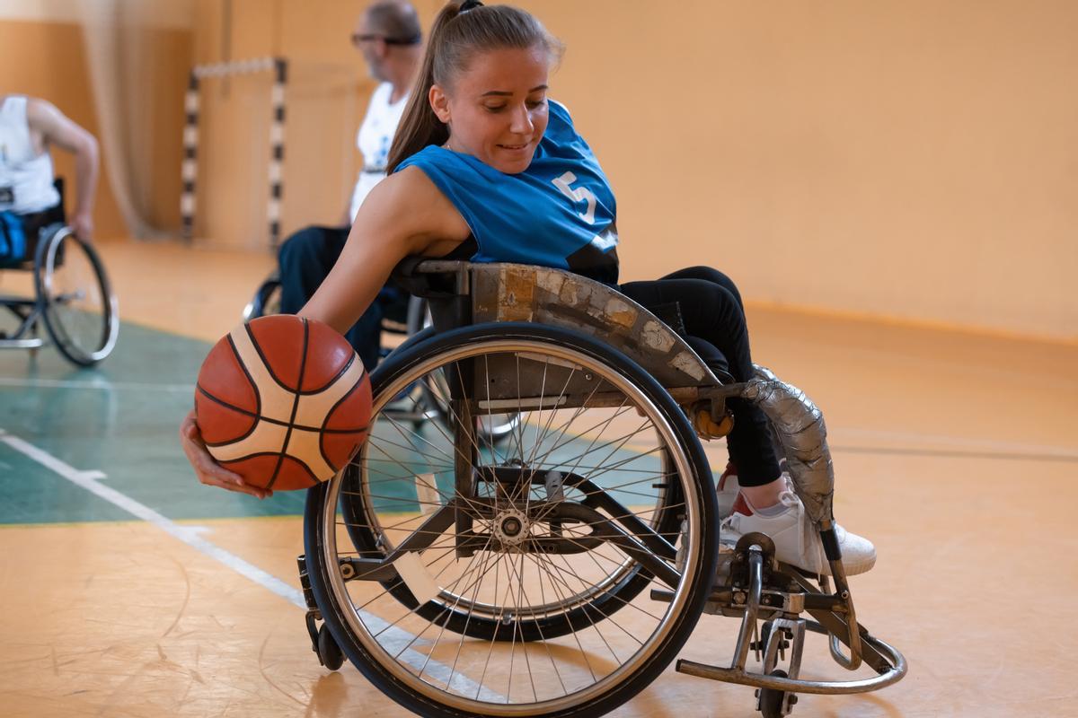 Una mujer practica baloncesto en un polideportivo.