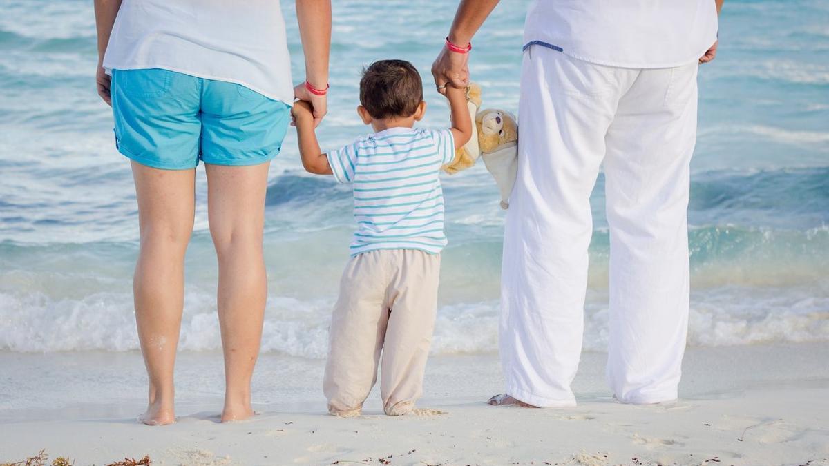 Imagen de archivo de un niño con su familia en la playa