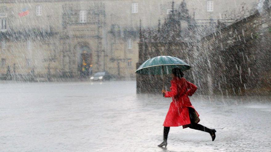 Una mujer cruza el Obradoiro bajo una fuerte tormenta.