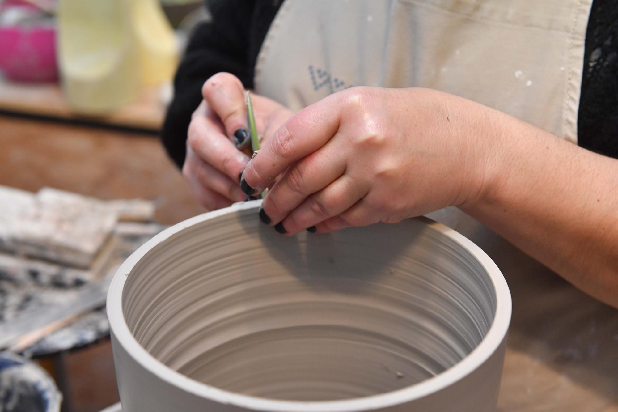 Laura Delgado con los vasos tiki ganadores, una combinación de culturas entre Polinesia y Galicia, y otras obras realizadas por esta ceramista en su taller de Cambre, en el que también da clases a pequeños grupos.