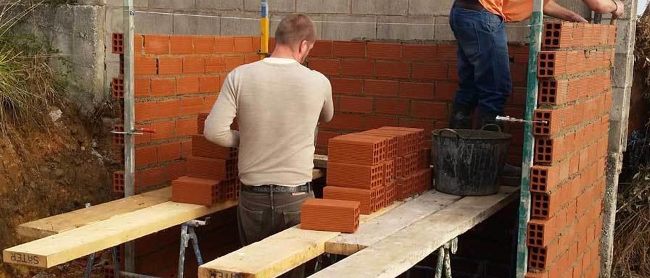 Operarios construyendo una garita a la entrada del monasterio de Lugones.