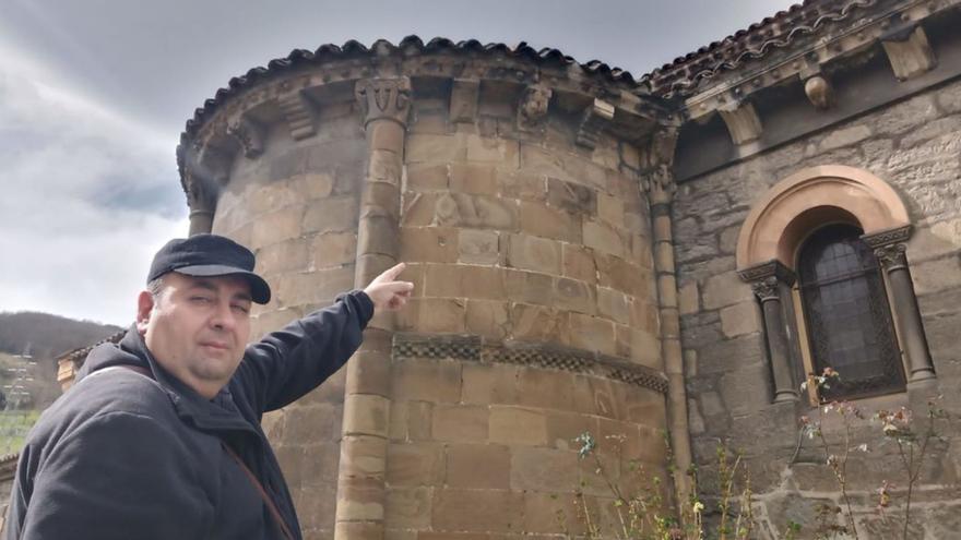 Fernando Oliva muestra el canecillo que alberga la talla de la rota, en un ábside de la iglesia de Ujo. | D. M.