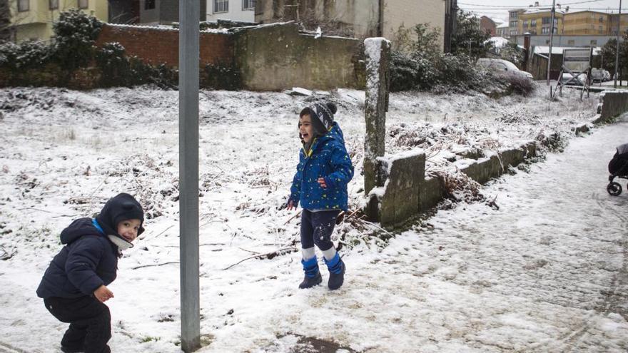 Dos niños juegan con la nieve en una calle de Lalín