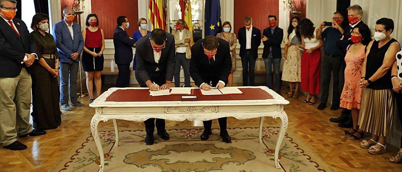 Enric Morera y Ximo Puig firman al acuerdo de reconstrucción en la sala de los Espejos del Palau dels Borja, sede de las Cortes Valencianas.