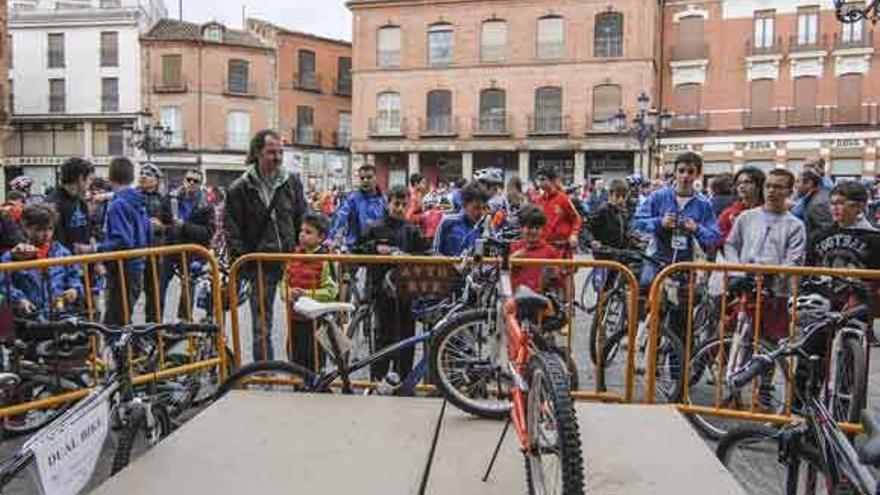 Chavales y niños participantes observan las bicicletas del sorteo en la Plaza Mayor.