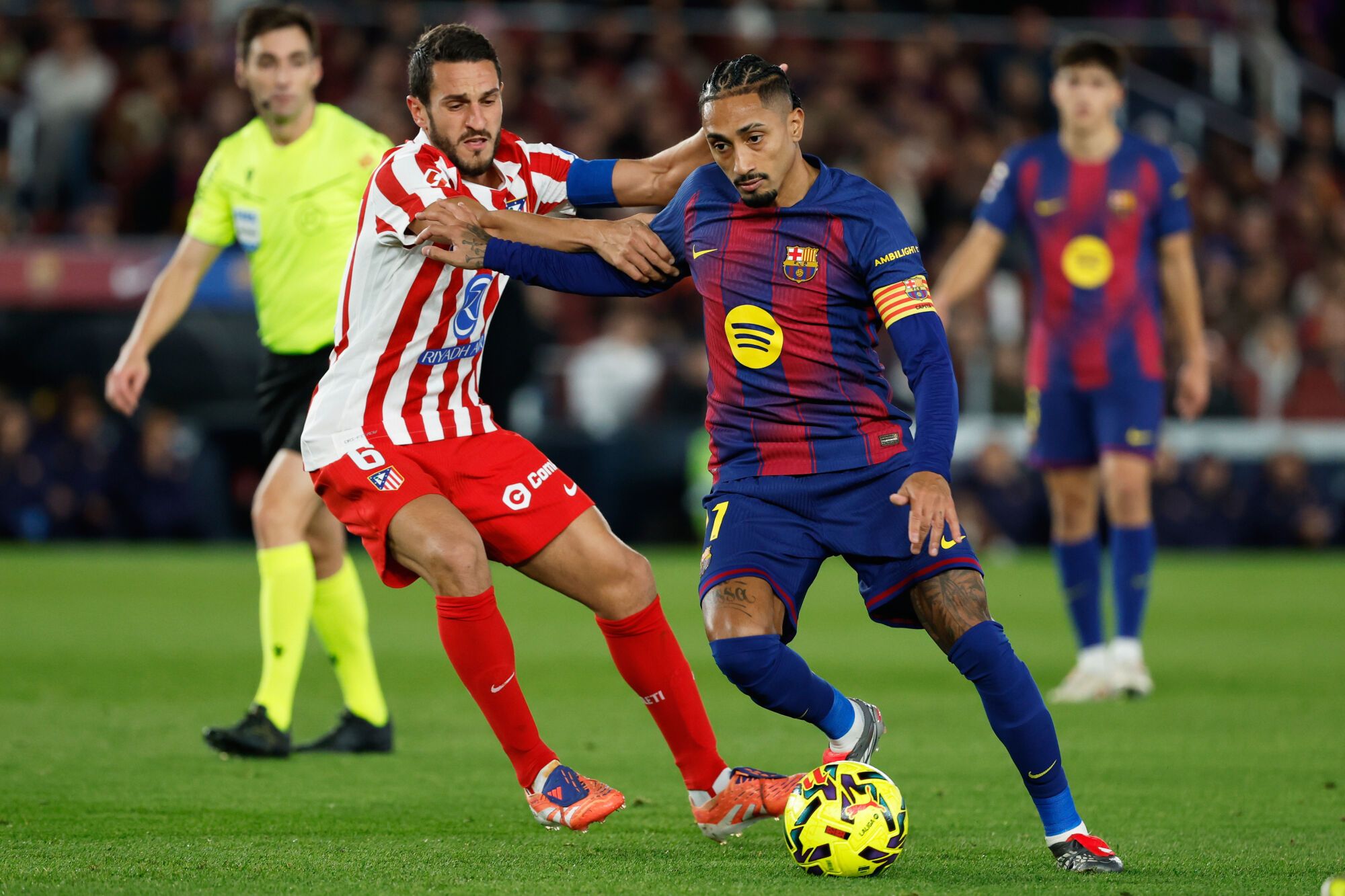 Atletico Madrid's Koke fights for the ball against Barcelona's Raphinha during a Spanish La Liga soccer match between Barcelona and Atletico de Madrid, in Barcelona, Spain, Tuesday, Dec.2, 2025. (AP Photo/Joan Monfort). EDITORIAL USE ONLY/ONLY ITALY AND SPAIN