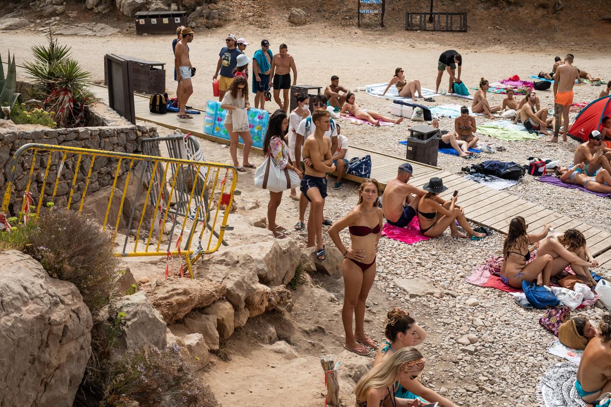 Bañistas esperando junto a la valla que cierra el acceso a Cala Saladeta.