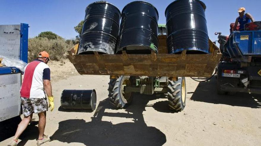 Operarios de la refinería CEPSA, de la factoría de Palos de la Frontera (Huelva), cargan bidones en un tractor para trasladarlos desde Matalascañas a la playa del Parque Nacional de Doñana donde realizan labores de recogida del crudo vertido accidentalmente el pasado jueves en la costa onubense. EFE/Julián Pérez