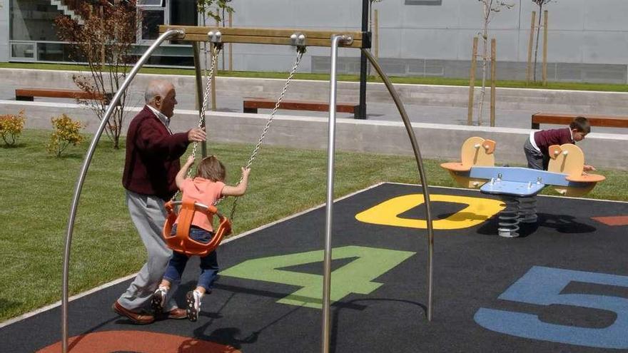 Un abuelo juega con sus nietos en un parque infantil en A Coruña.