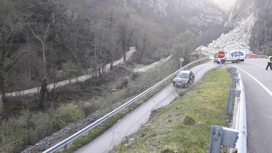 Un turismo y un camión de reparto acceden al paso provisional desde el Corredor, con el argayo al fondo.