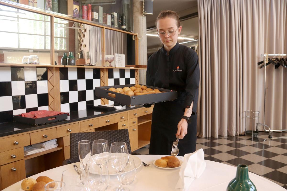 Una alumna de l'Escola d'Hostaleria i Turisme de Girona practica com servir el pa a taula
