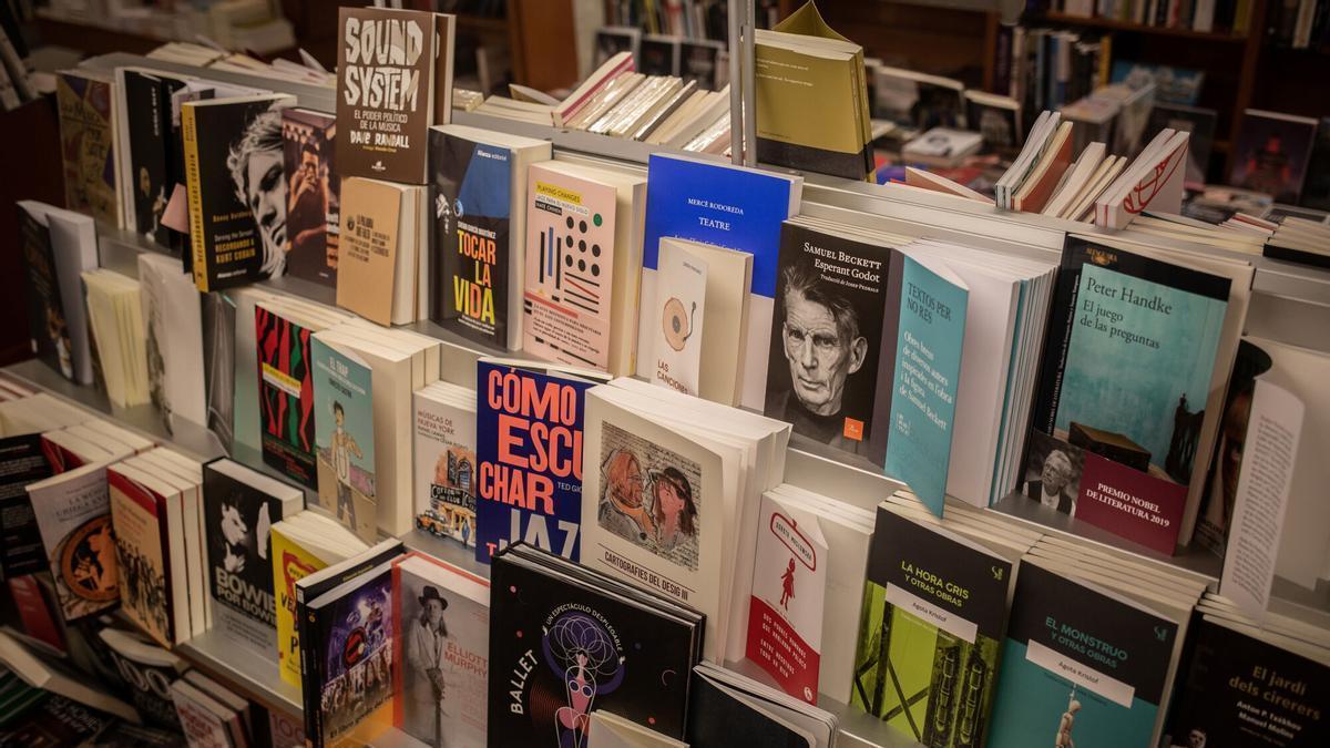 Libros y material colocado en las estanterías de la librería Laie Pau Claris.