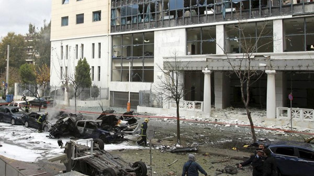 Bomberos y policías inspeccionan la zona en la que ha estallado la bomba, frente a los tribunales de justicia de asuntos administrativos, este jueves, en Atenas.