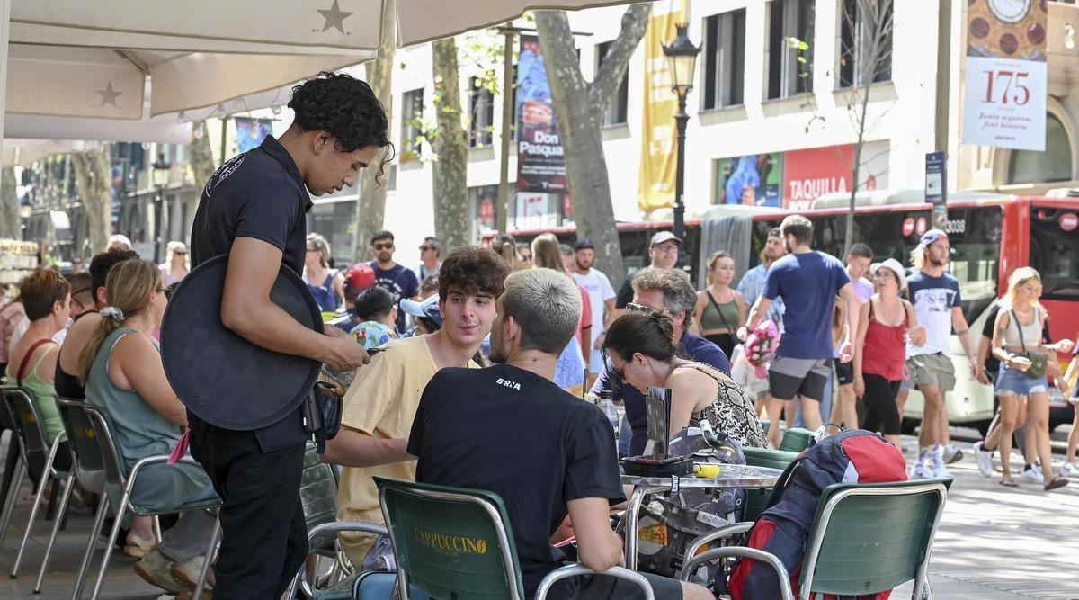 Un camarero cobra con tarjeta a unos clientes en una terraza frente al Liceu, en Barcelona.