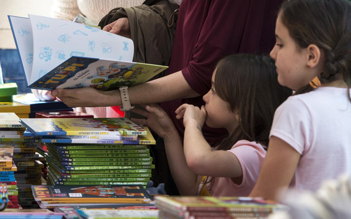 Una nena consulta diversos llibres en companyia del seu pare.