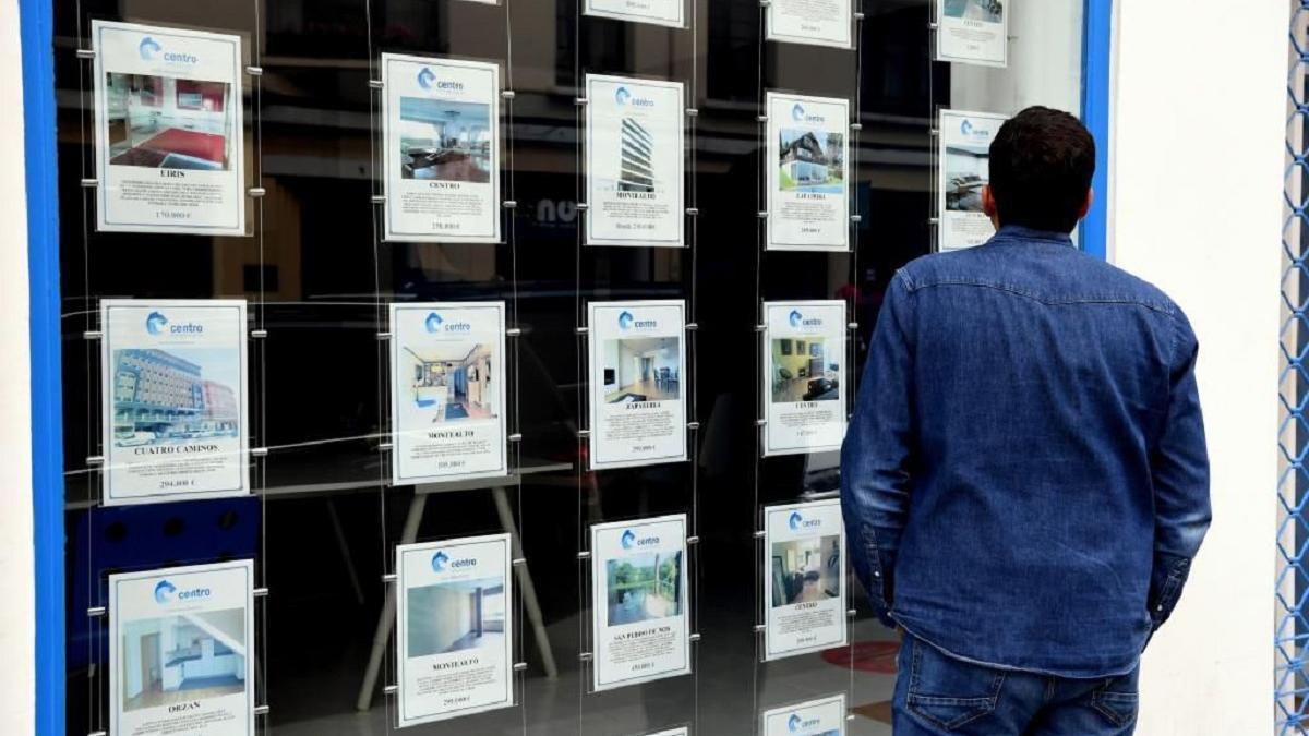 Un hombre observa ofertas de venta de pisos en una inmobiliaria. 