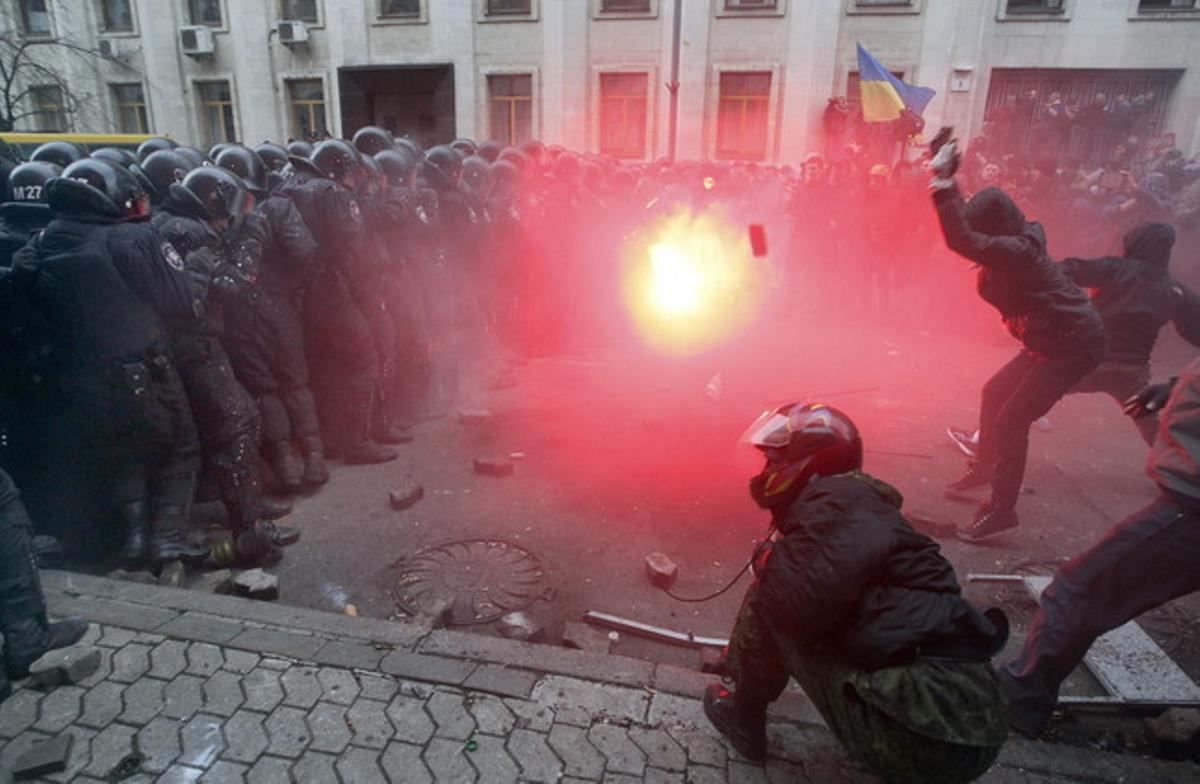 Los manifestantes lanzan un artefacto incendiario al muro que la policía ha hecho frente al edificio de administración presidencial.