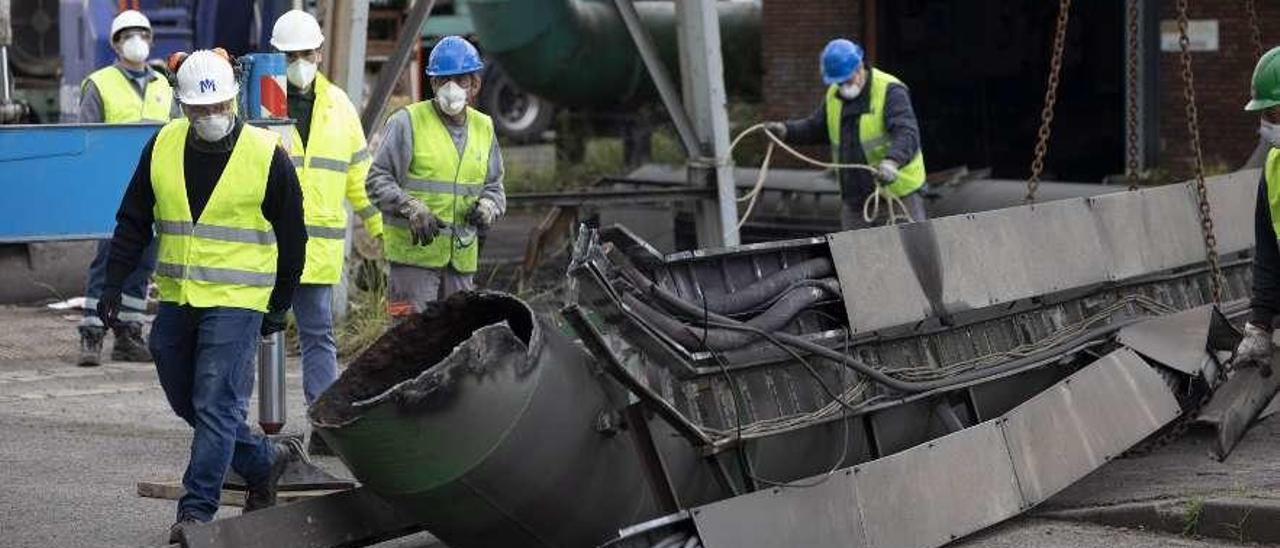 Empleados de la empresa contratada por Sepides para demoler la estación de bombeo de agua de las baterías de coque, con una tubería recién cortada.