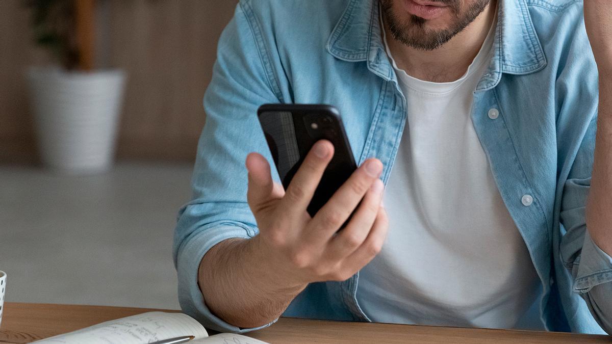 Un hombre consulta su teléfono móvil.