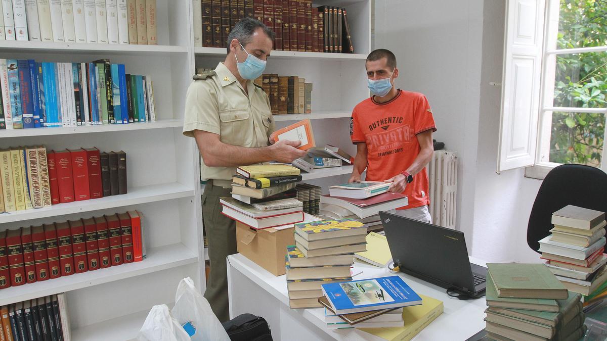 El subteniente José Duque, con Alejandro Montero, el trabajador que se encarga de ordenar la biblioteca de la subdelegación. // IÑAKI OSORIO