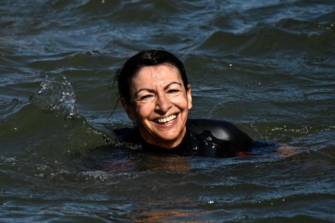 TOPSHOT - Paris Mayor Anne Hidalgo swims in the Seine, in Paris on July 17, 2024, to demonstrate that the river is clean enough to host the outdoor swimming events at the Paris Olympics later this month. Despite an investment of 1.4 billion euros ($1.5 billion) to prevent sewage leaks into the waterway, the Seine has been causing suspense in the run-up to the opening of the Paris Games on July 26 after repeatedly failing water quality tests. But since the beginning of July, with heavy rains finally giving way to sunnier weather, samples have shown the river to be ready for the open-water swimming and triathlon -- and for 65-year-old Hidalgo. (Photo by JULIEN DE ROSA / AFP)