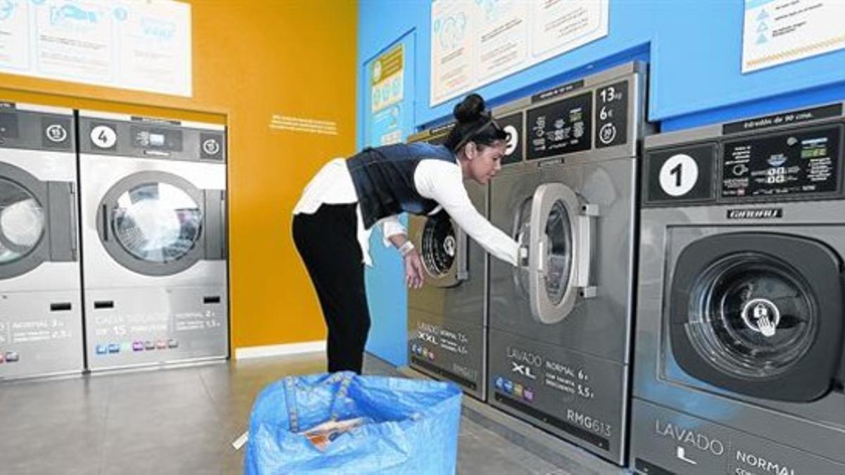 Una clienta mete la ropa en la lavadora de un autoservicio del barrio de Horta.