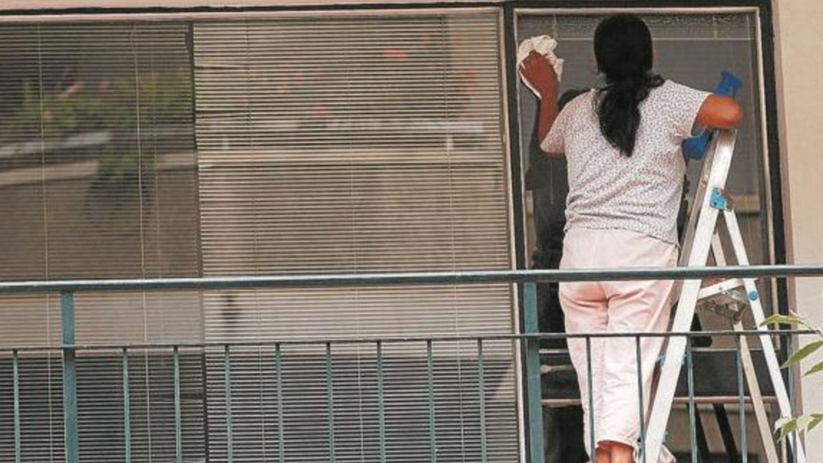 Una empleada de hogar limpiando una ventana. |   // L.O.