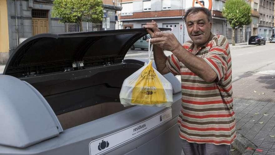 &quot;Lan&quot; Escudero, vecino de El Entrego, deposita una bolsa de basura en un contenedor.