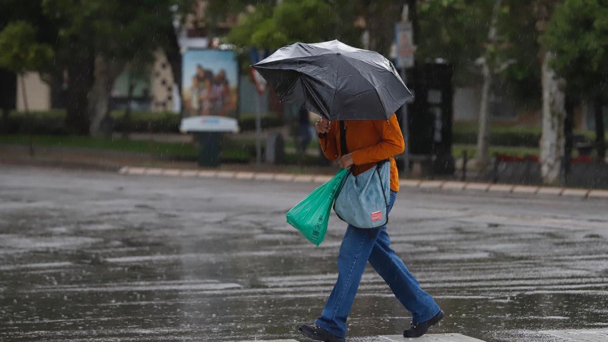 Una mujer se refugia de la lluvia en una calle de Córdoba.