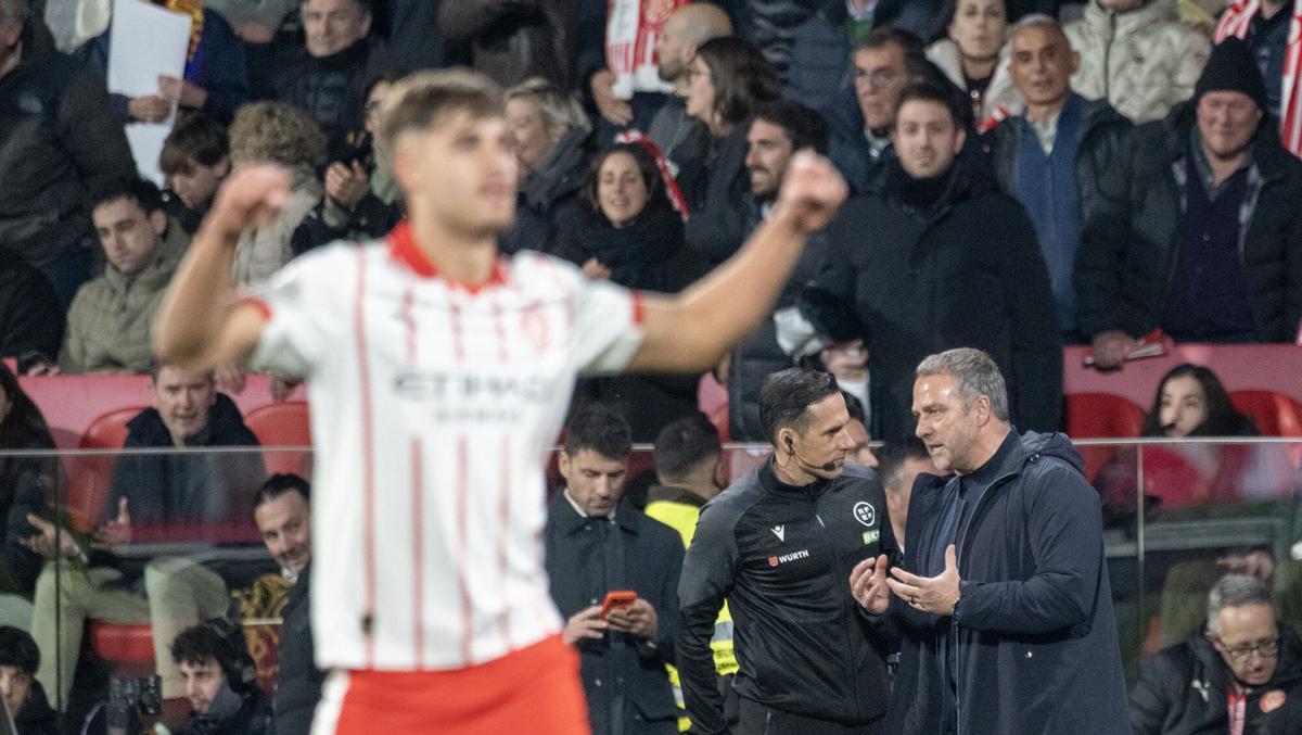 Hansi Flick pide explicaciones al cuarto árbitro en la banda mientras los jugadores del Girona celebran el segundo gol.