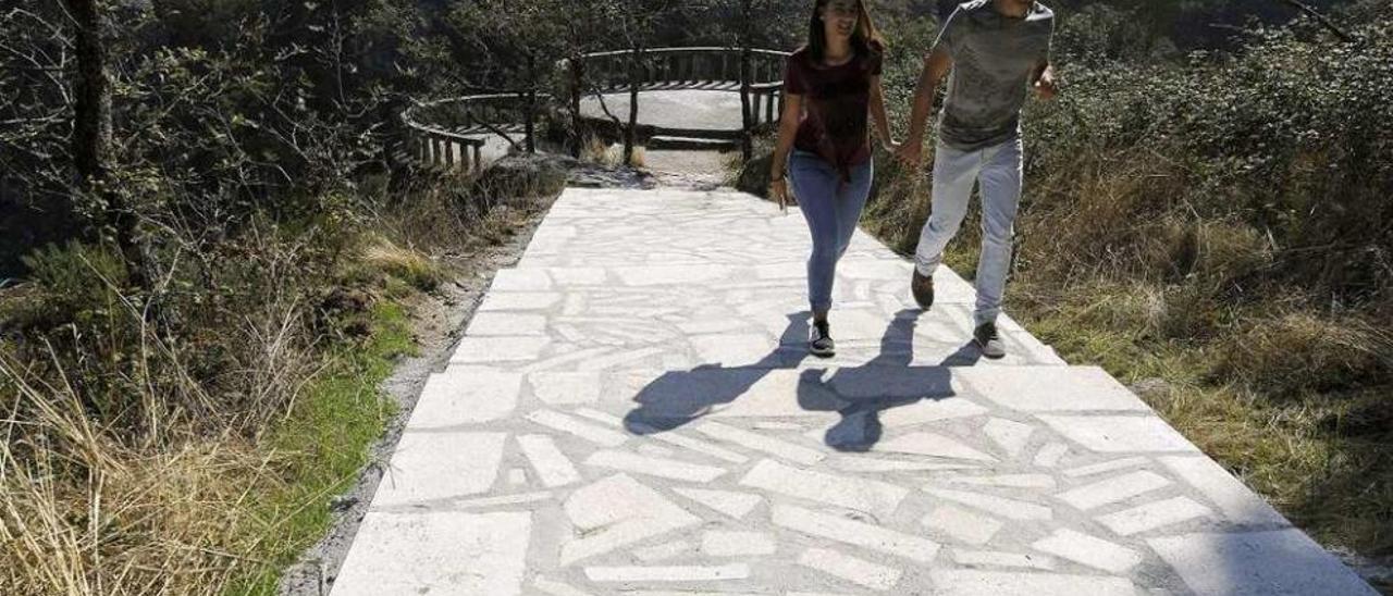 Una pareja de jóvenes sube las escaleras de acceso al mirador de la catarata. // Bernabé/Javier Lalín