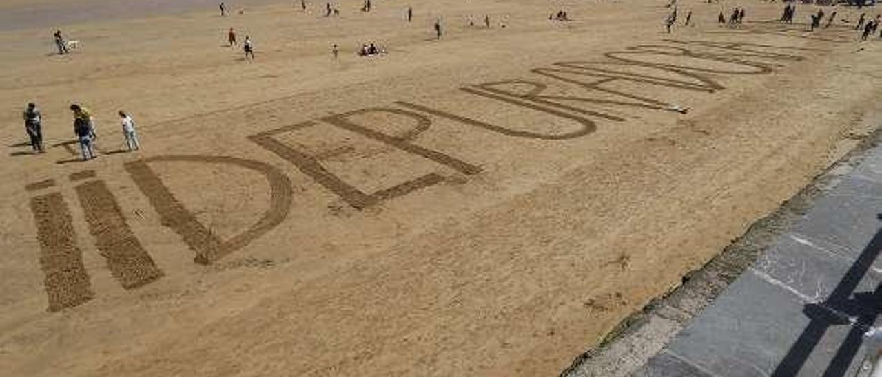 Reivindicación con el lema &quot;¡¡Depuradora ya!!&quot; escrito en la arena de la playa de San Lorenzo el pasado abril por un grupo de ecologistas.