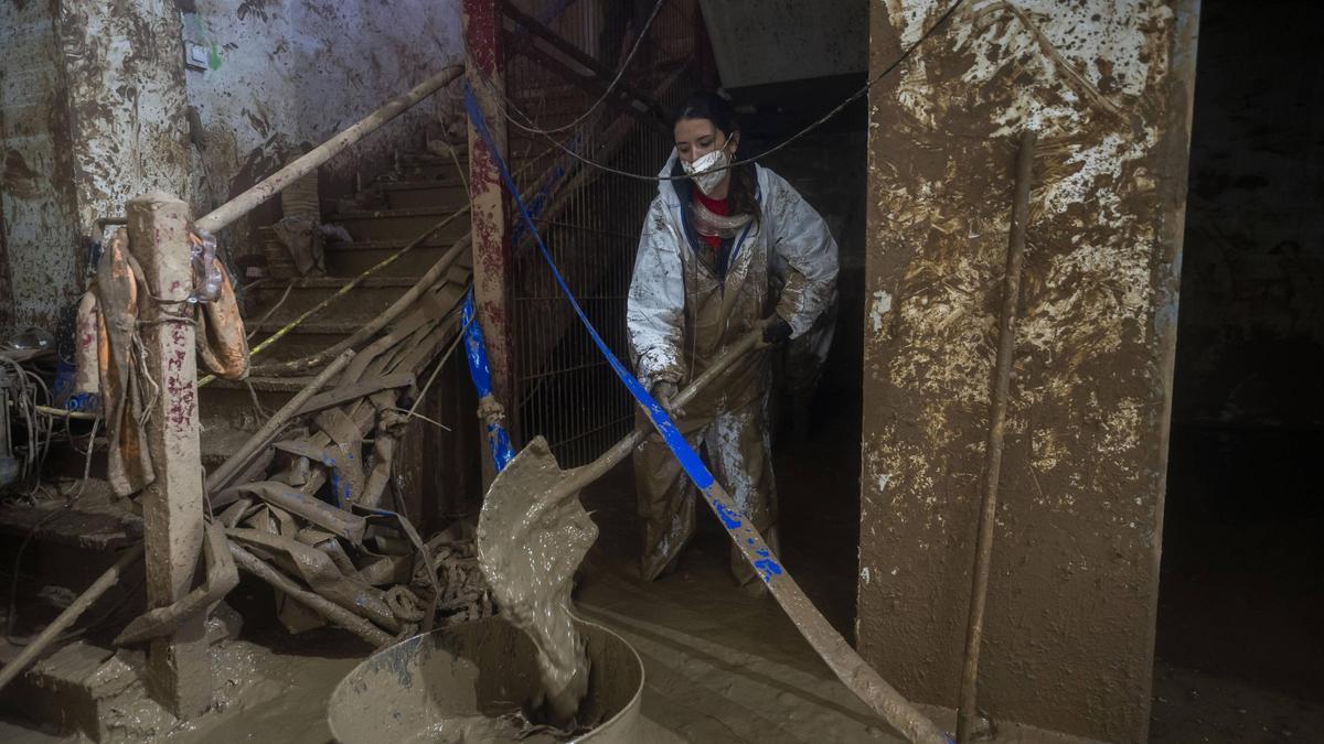 Una voluntaria retira lodo de un edificio afectado por la dana.
