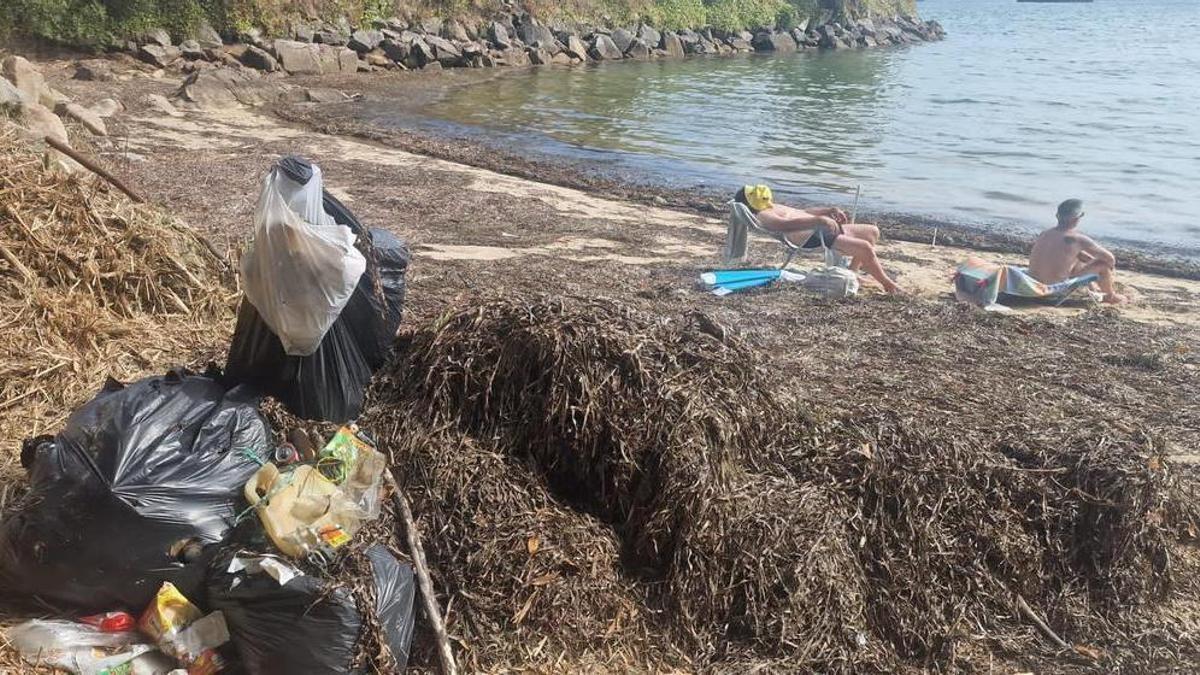 Estado de la playa do Mouro, en Domaio, llena de algas y basura.