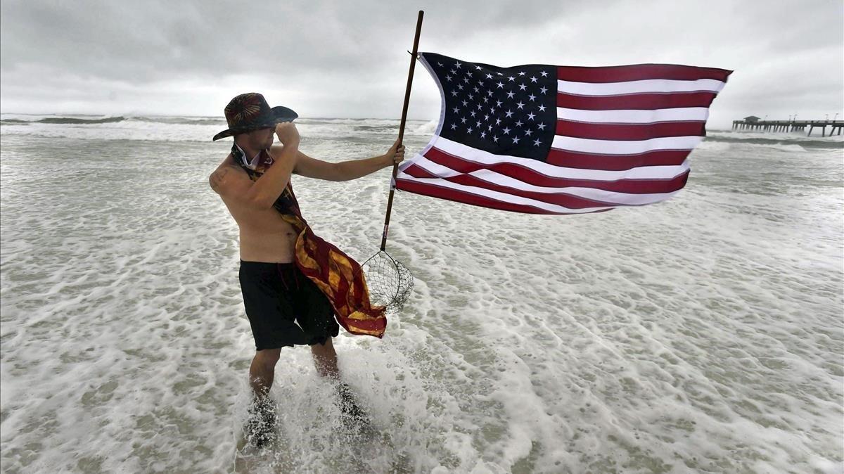 Corbin Boyce sostiene una bandera estadounidense en medio de las inundaciones del huracán Sally. 