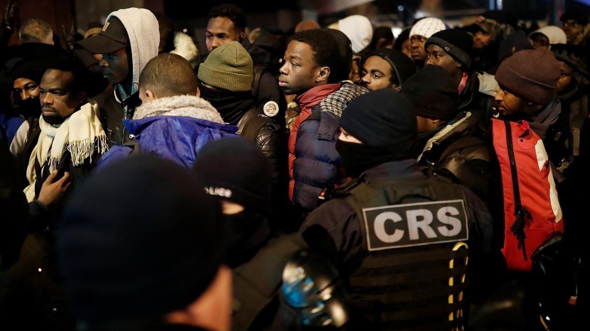 Los inmigrantes hacen cola mientras la policía francesa evacua a cientos de ellos de un campamento improvisado en Saint-Denis, a las afueras de París